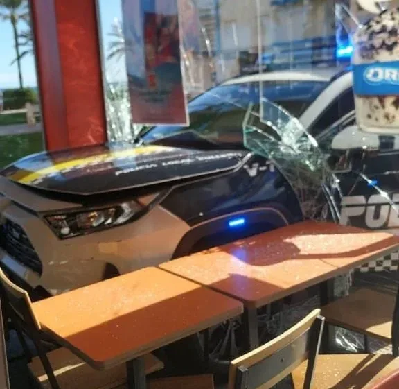 Un coche de la Policía Local de Cullera se estampa contra un Burger King junto al paseo