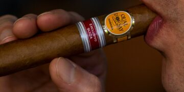 person holding brown and red labeled bottle