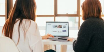 two women talking while looking at laptop computer