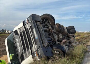 Un camión vuelca sobre un campo en el vial de servicio de la V21 en Alboraya