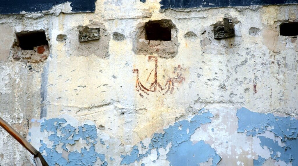 Detalle del grafiti medieval Barco del pequeño Juan en la calle Bolsería de Valencia, pintado en rojo almagra con un ángel en la proa.