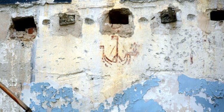 Detalle del grafiti medieval Barco del pequeño Juan en la calle Bolsería de Valencia, pintado en rojo almagra con un ángel en la proa.