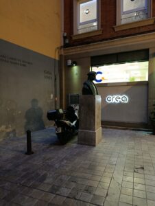 Motocicleta aparcada detr&aacute;s del busto de Luis Vives en Valencia, invadiendo el entorno monumental.