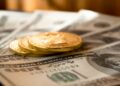 three round gold-colored coins on 100 US dollar banknotes